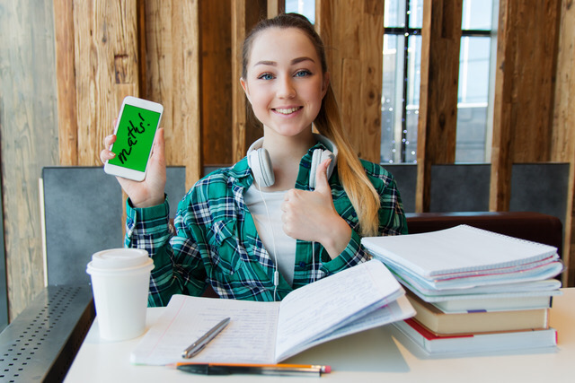 Canva smiling woman holding white android smartphone while sitting front of table